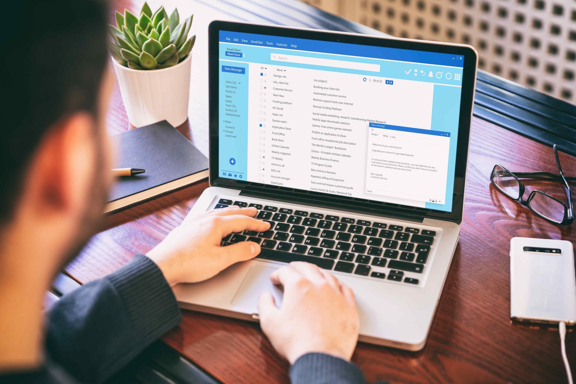 A man is typing on a laptop computer at a desk.