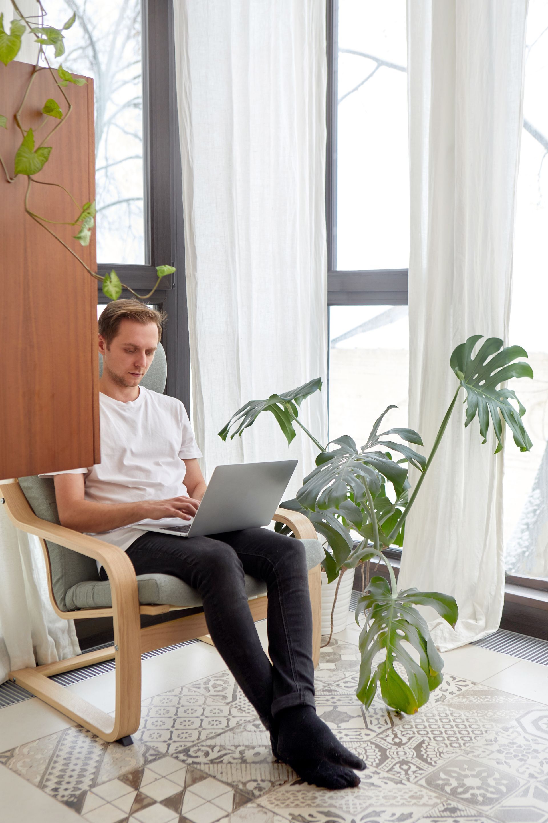 A man is sitting in a chair using a laptop computer for his coaching business.