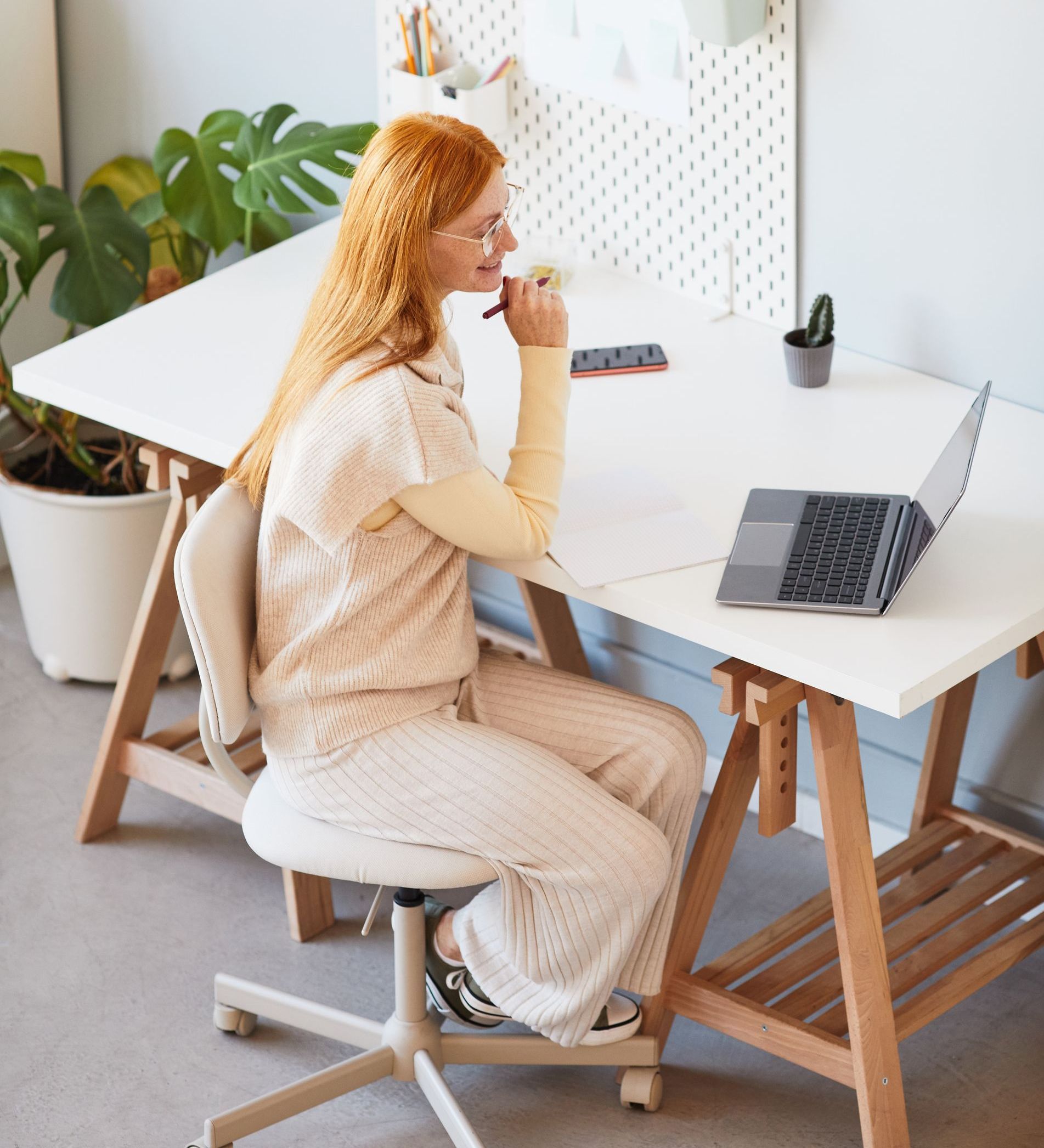 A woman is sitting at a desk with a laptop on it while talking to coaching clients.
