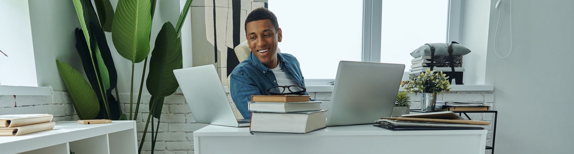 A man is sitting at a desk in front of a laptop computer coaching clients.
