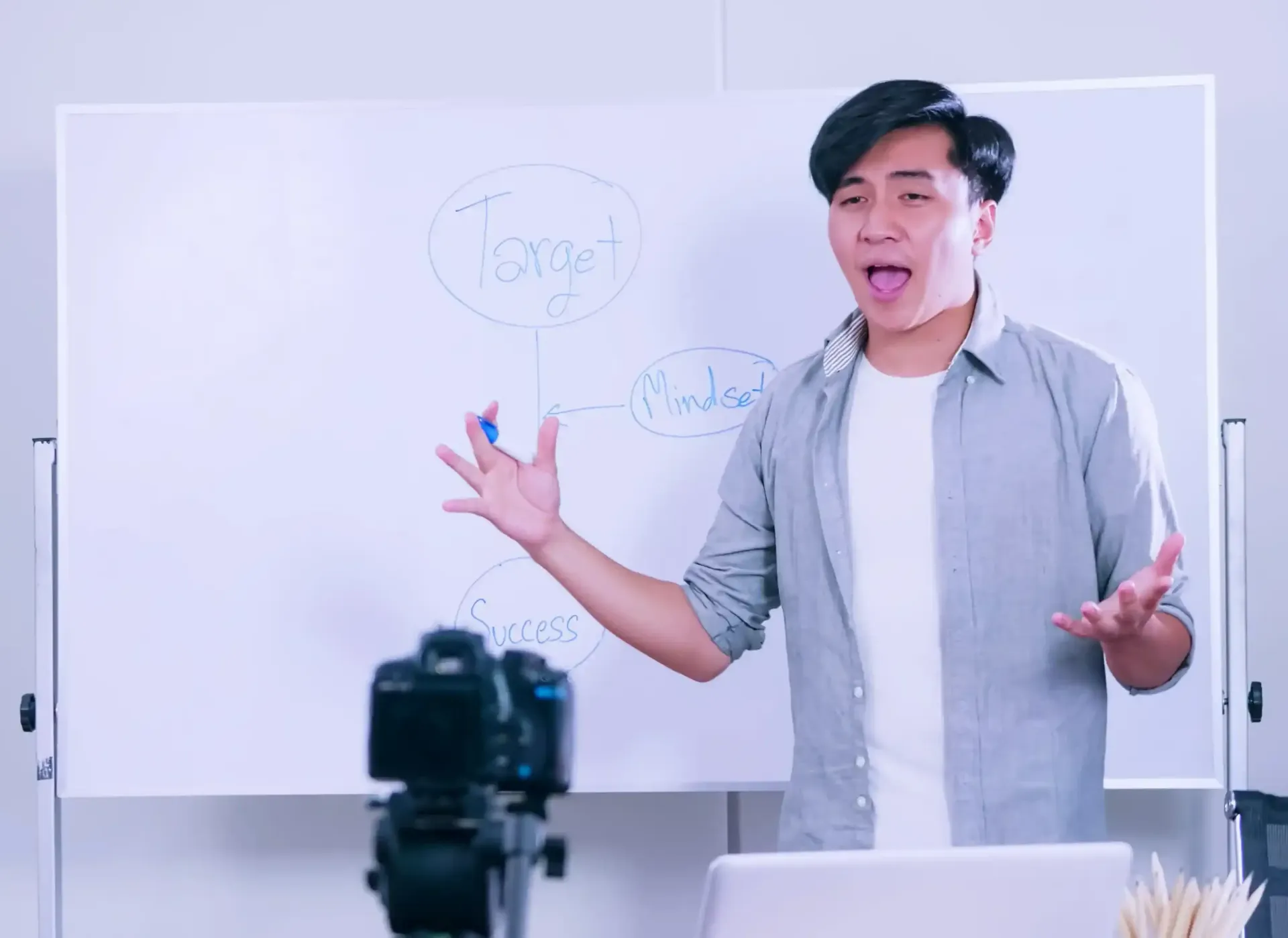 A man is standing in front of a whiteboard teaching a masterclass.