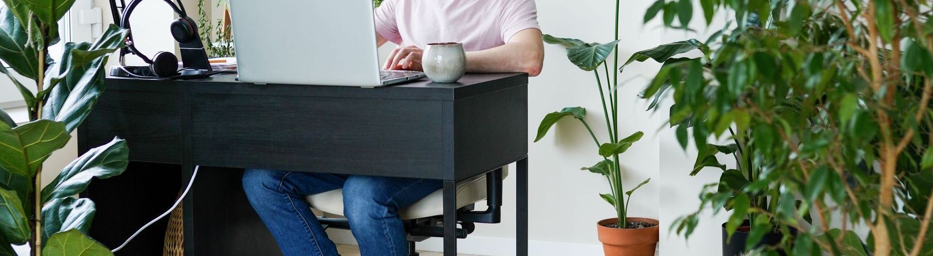 A man is sitting at a desk with a laptop and a cup of coffee working on his coaching business.
