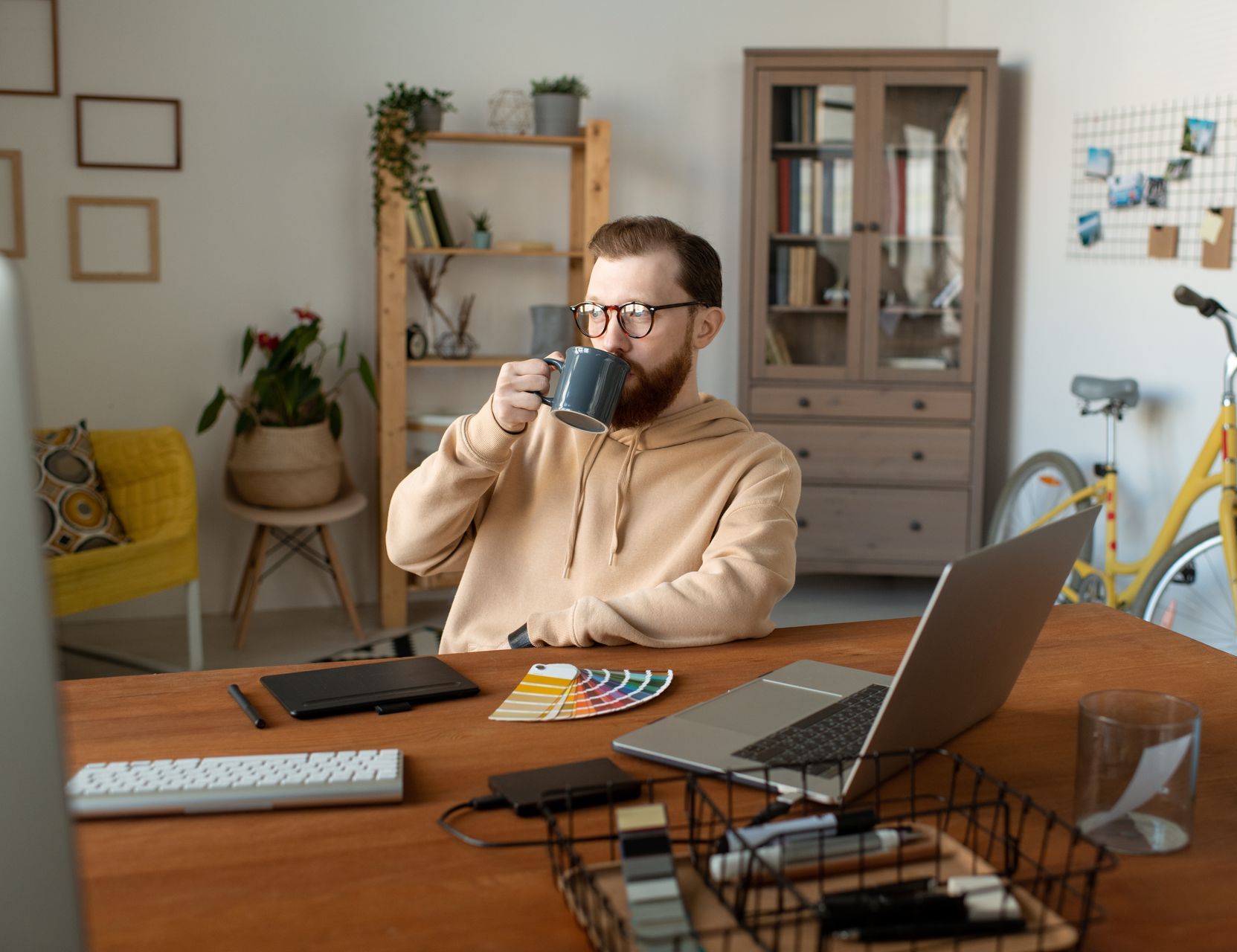 A man is sitting at a desk drinking a cup of coffee while he thinks about how he can use AI to gain more leads in his Coaching business.