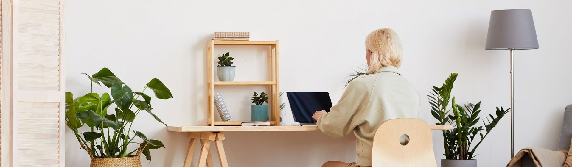 A woman is sitting at a desk using a laptop computer for coaching clients.