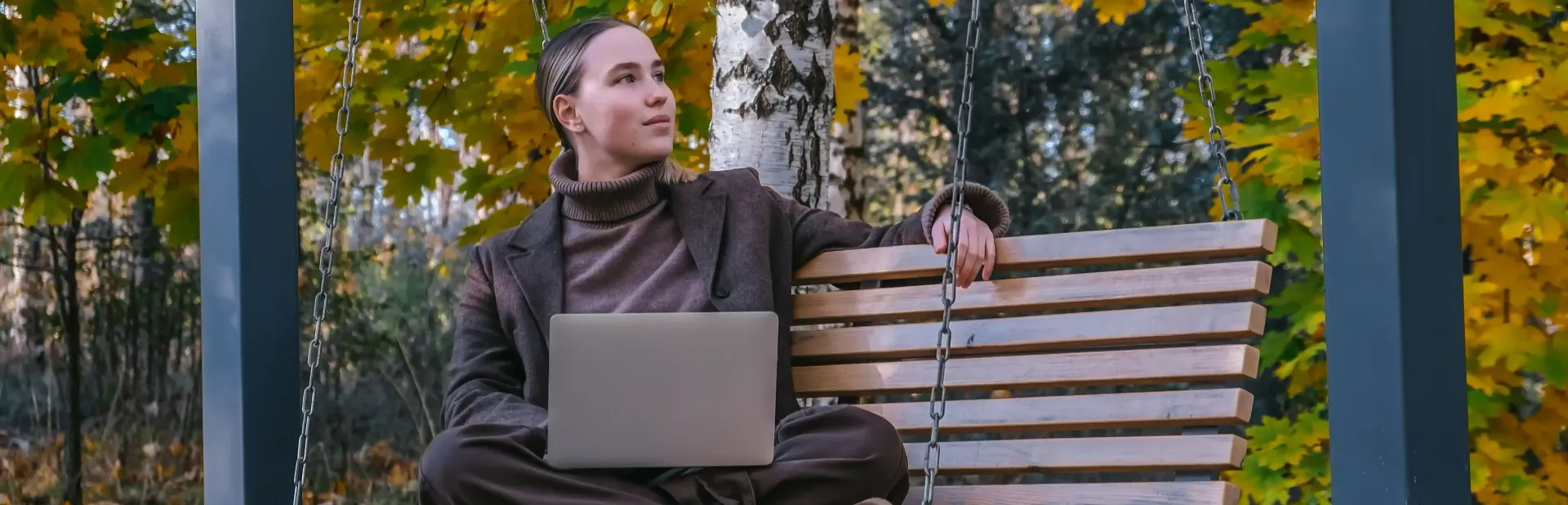 A woman is sitting on a bench with a laptop.