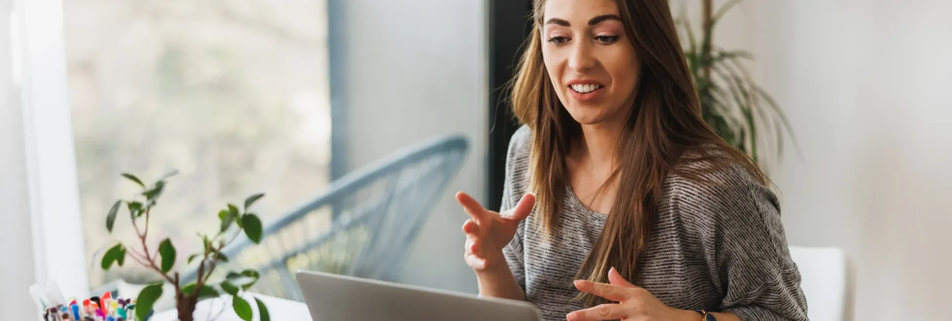 A woman is sitting at a table using a laptop computer teaching a masterclass.
