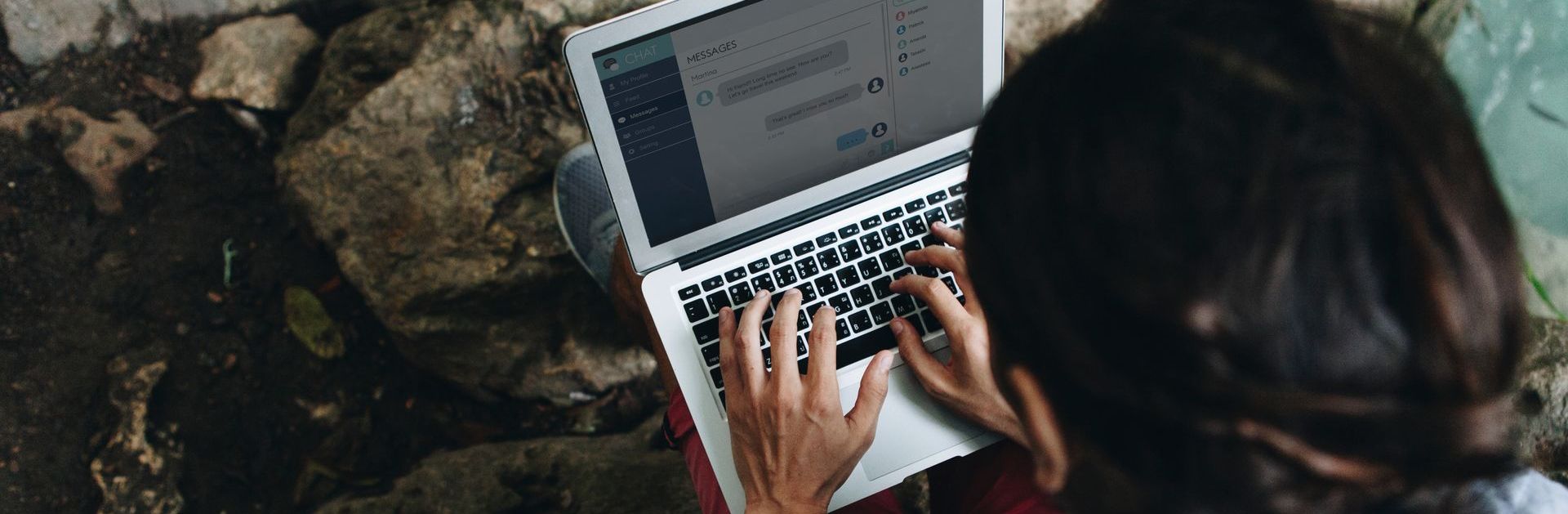 A woman is typing on a laptop computer creating evergreen content while sitting on the ground.
