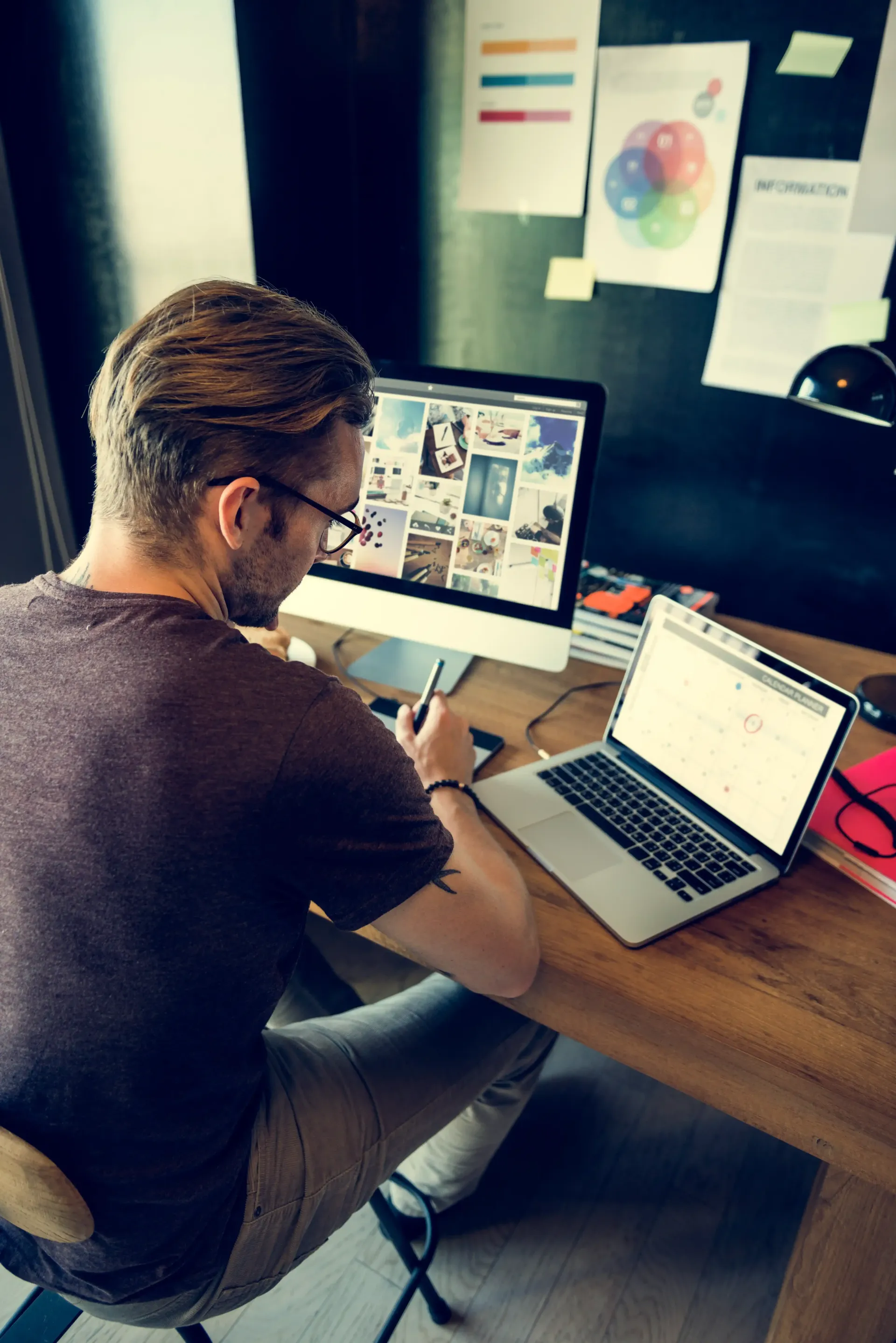 A man is sitting at a desk with a laptop and a computer.