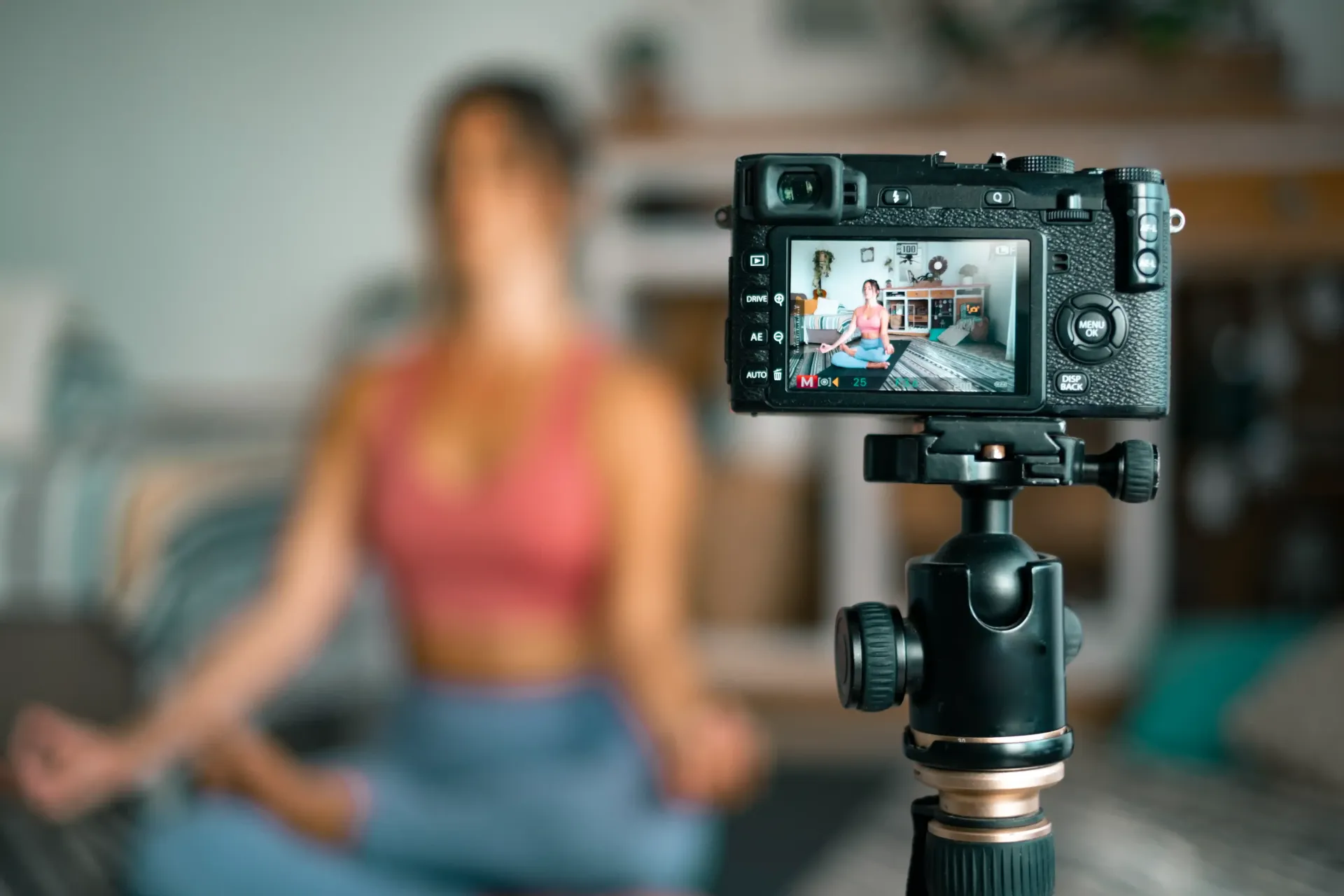 A woman is sitting in a lotus position in front of a camera.