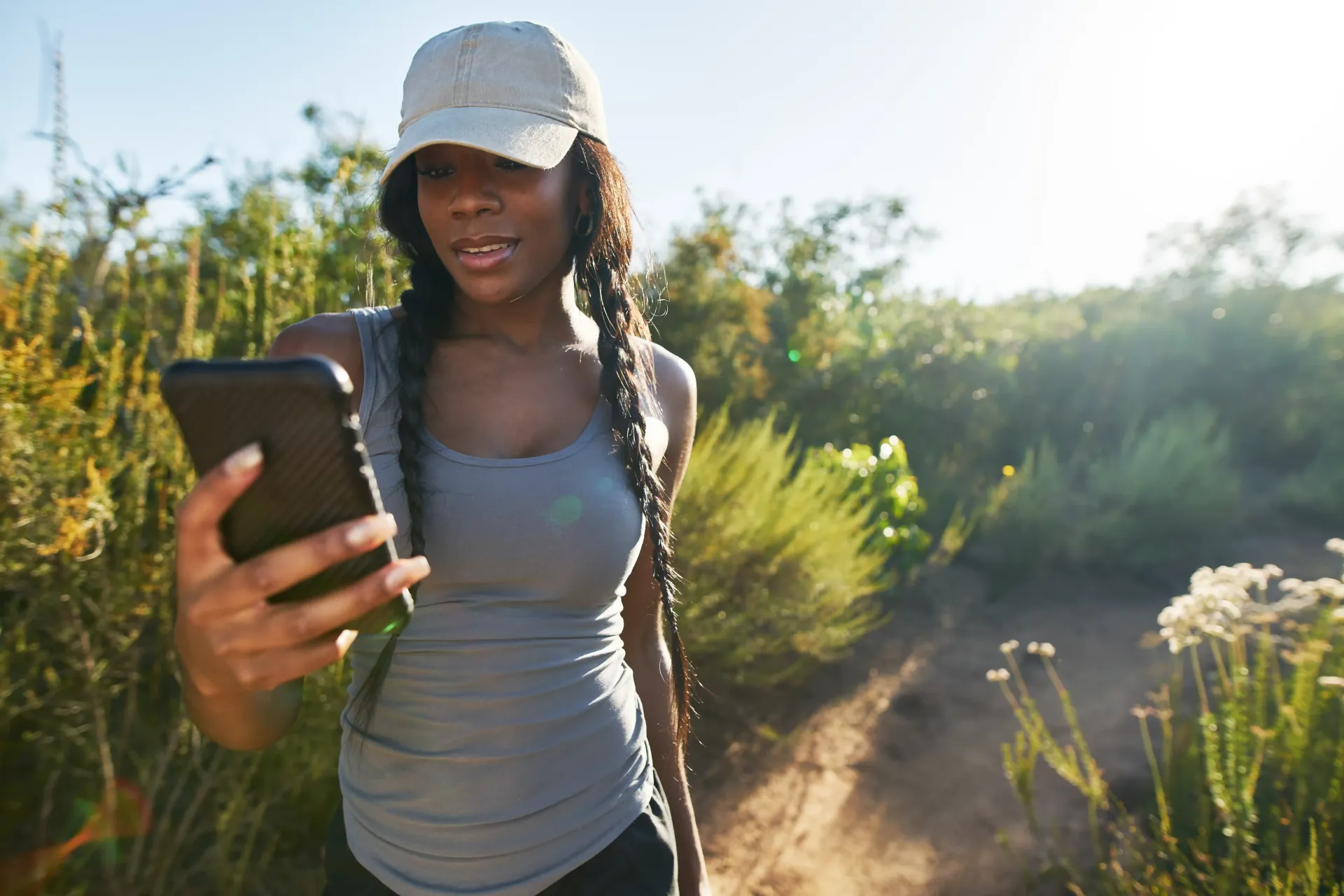 A woman is taking a selfie with her cell phone in the woods.