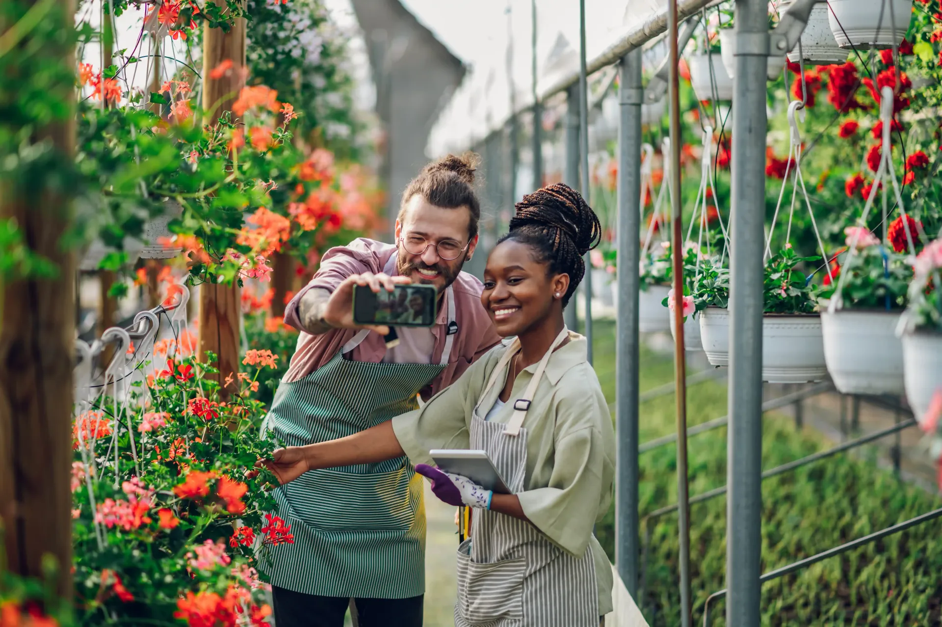 A man and a woman are taking a selfie in a greenhouse.