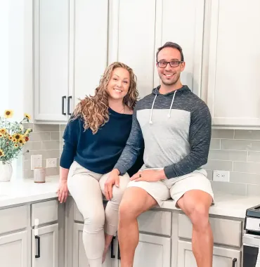 Owners of AP Digital Service- Amanda and Peter,  are sitting on a counter in a kitchen in support of their SEO and Evergreen services for content creators to scale beyond social media.