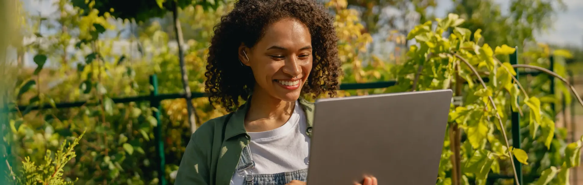 A woman is using a laptop computer in a garden.
