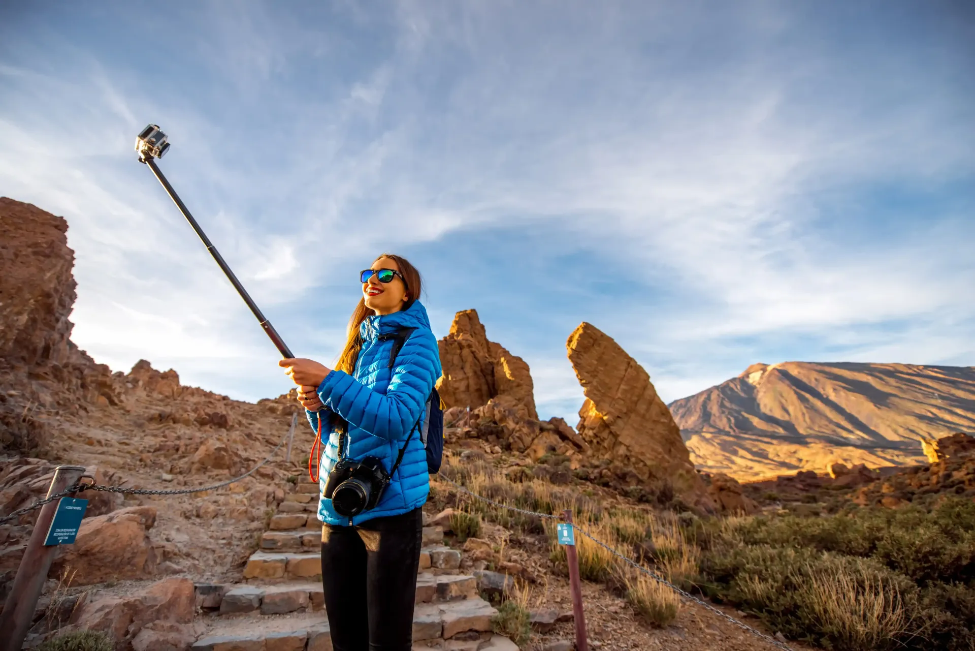 A woman is taking a selfie with a tripod in the desert.