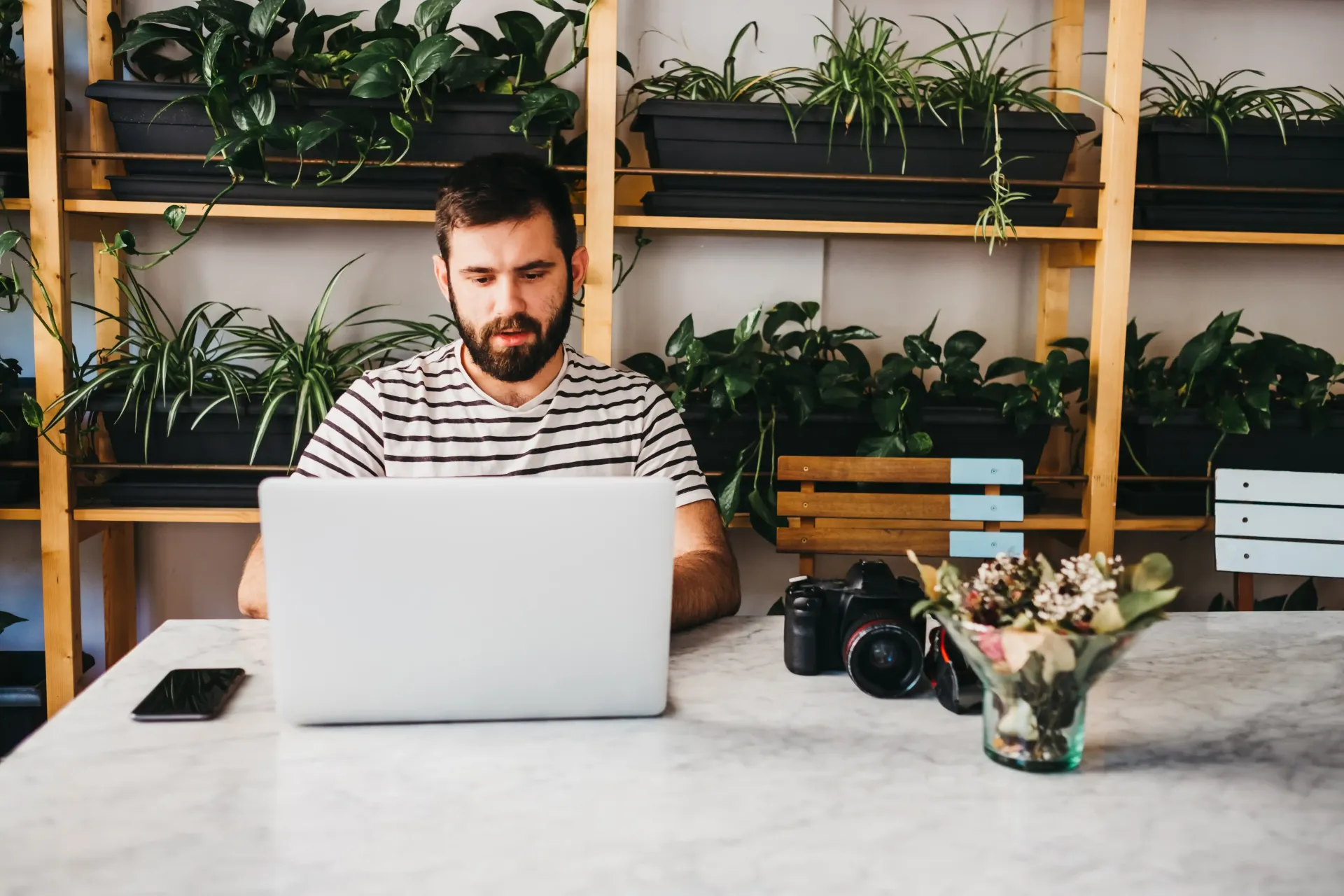 A man is sitting at a table using a laptop computer.