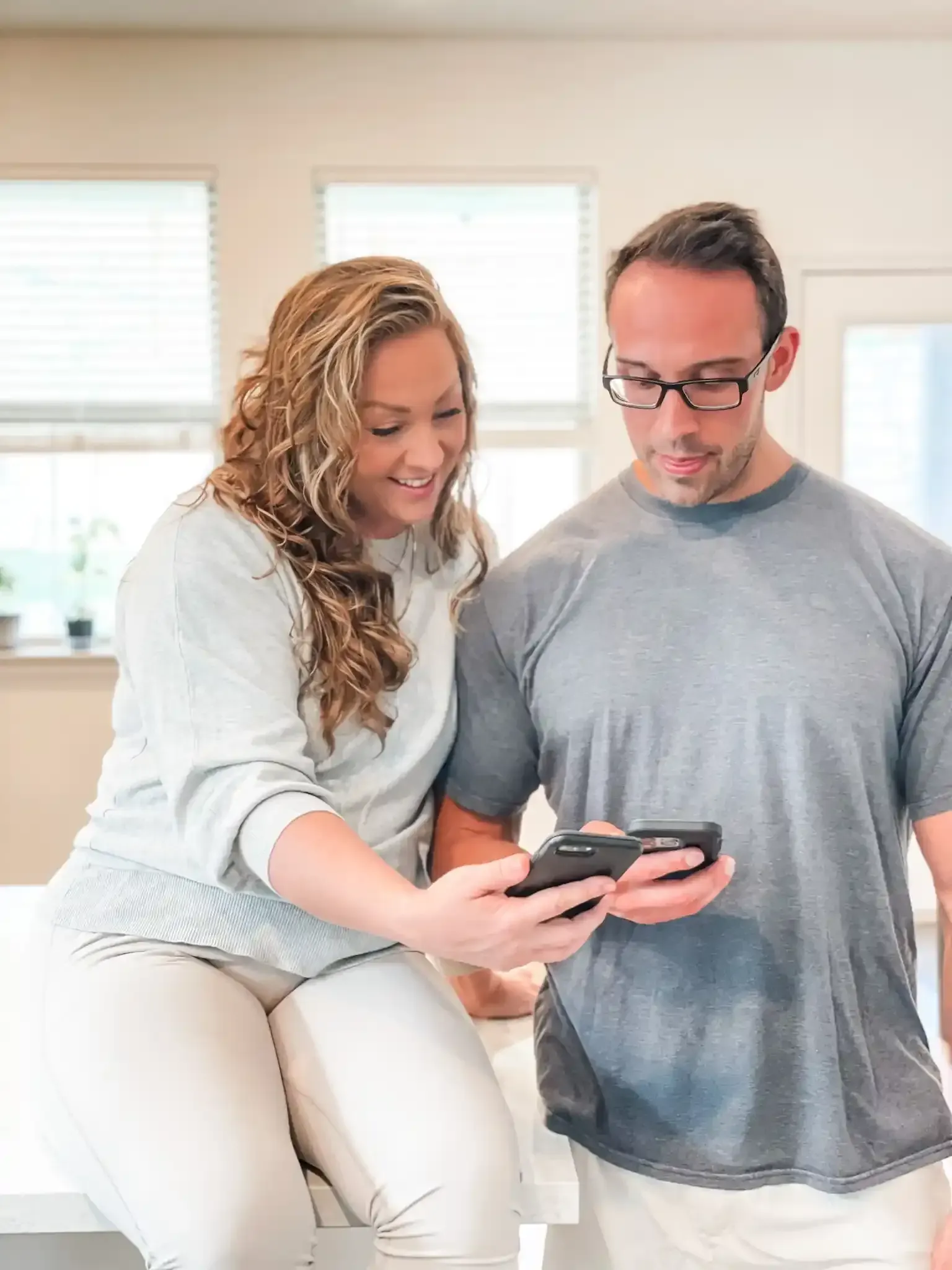 Peter and Amanda working together on cell phones to aid their clients' success with AI visibility.