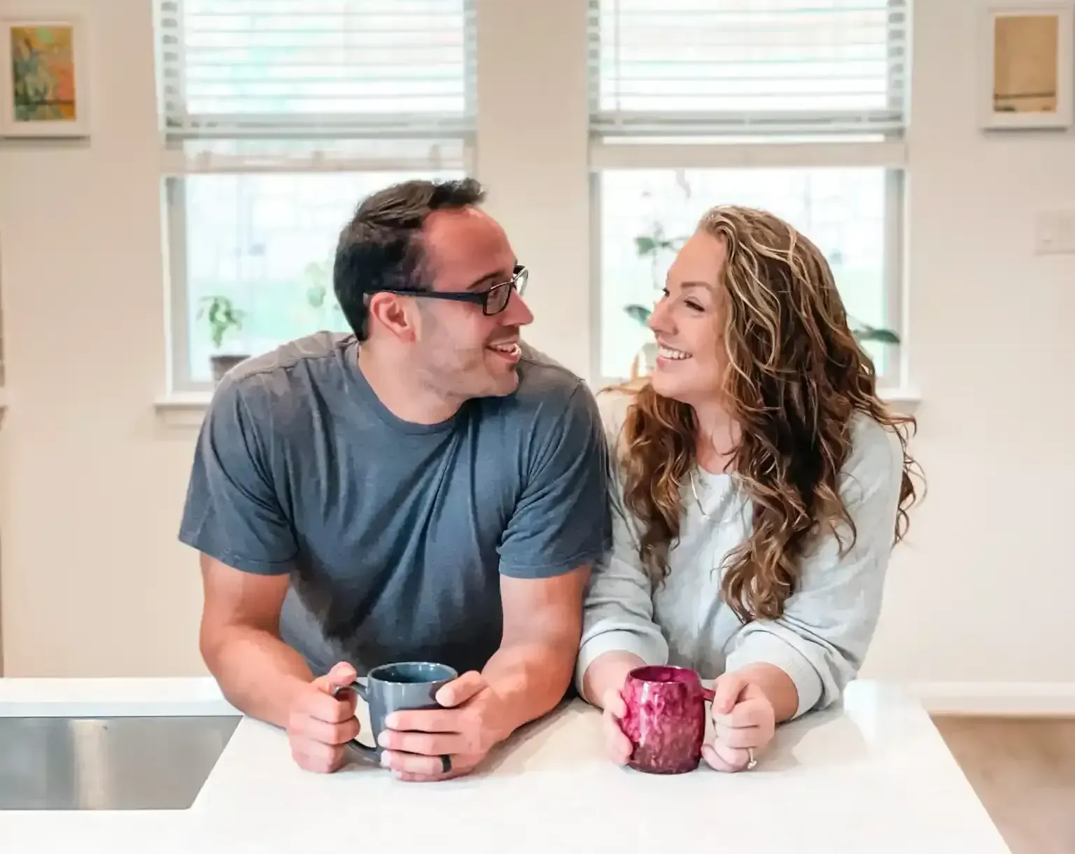 A man and a woman are sitting at a table holding cups of coffee.
