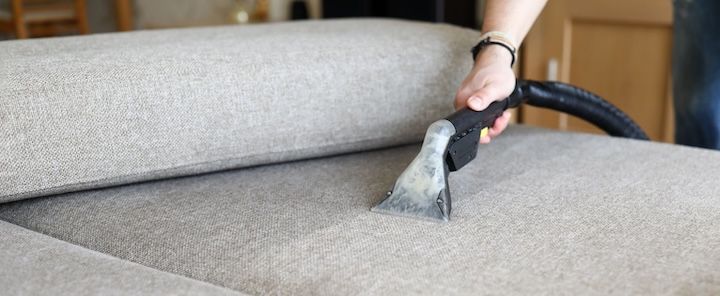 Someone cleaning upholstery with a cleaning device