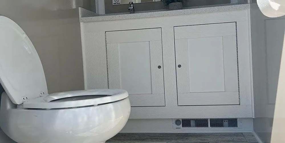 A white toilet with the seat open, next to a white cabinet in a bathroom.