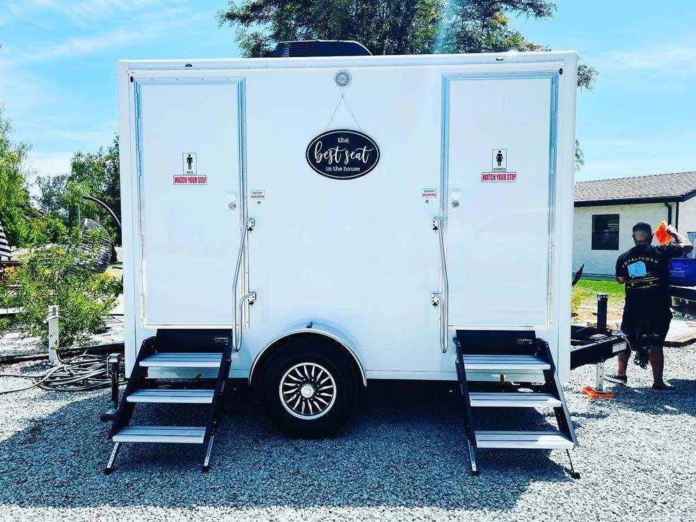 White trailer with two restroom doors. Person nearby.