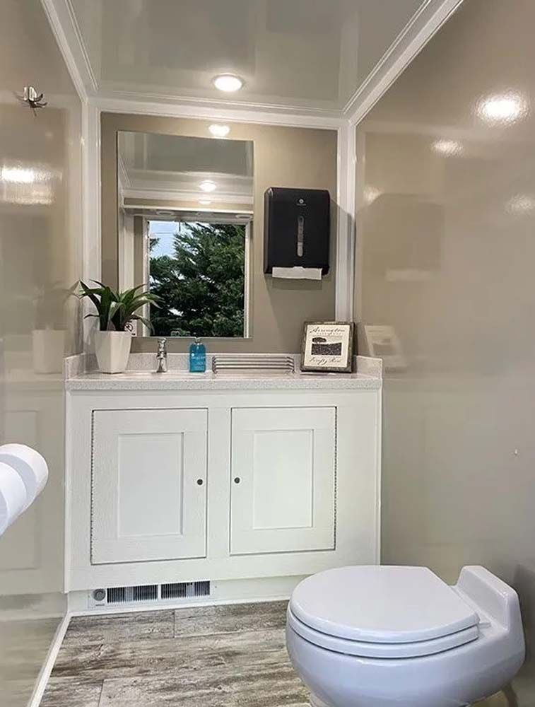 Inside of a clean, white bathroom, a toilet and sink area with a window.