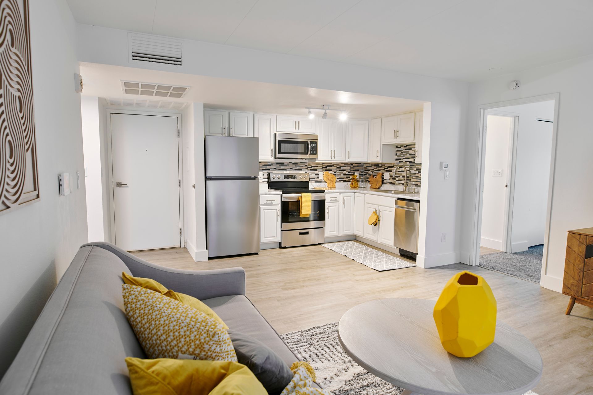 A living room with a couch and a yellow vase on a table.