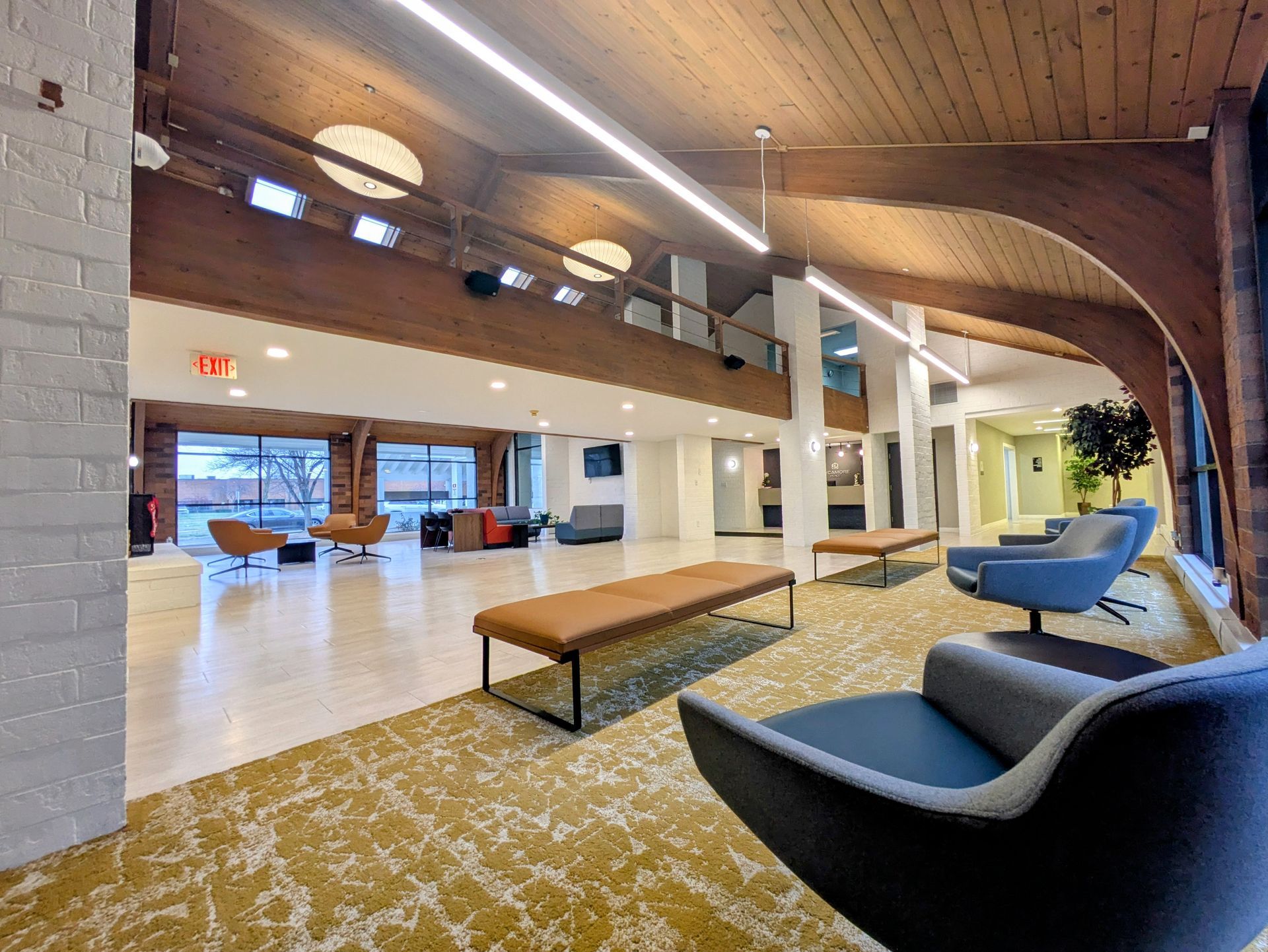 There are many chairs and benches in the lobby of a hotel.