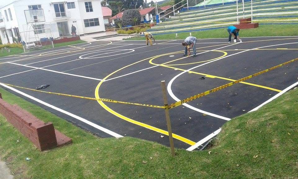 Casa moderna blanca con puerta y contraventanas de madera, entrada para vehículos y exuberante vegetación.