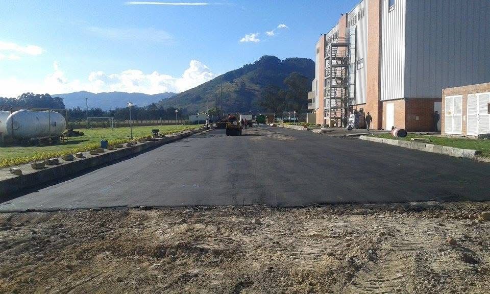 Manos de un trabajador colocando gránulos, primer plano. Asfalto gris con líneas blancas.