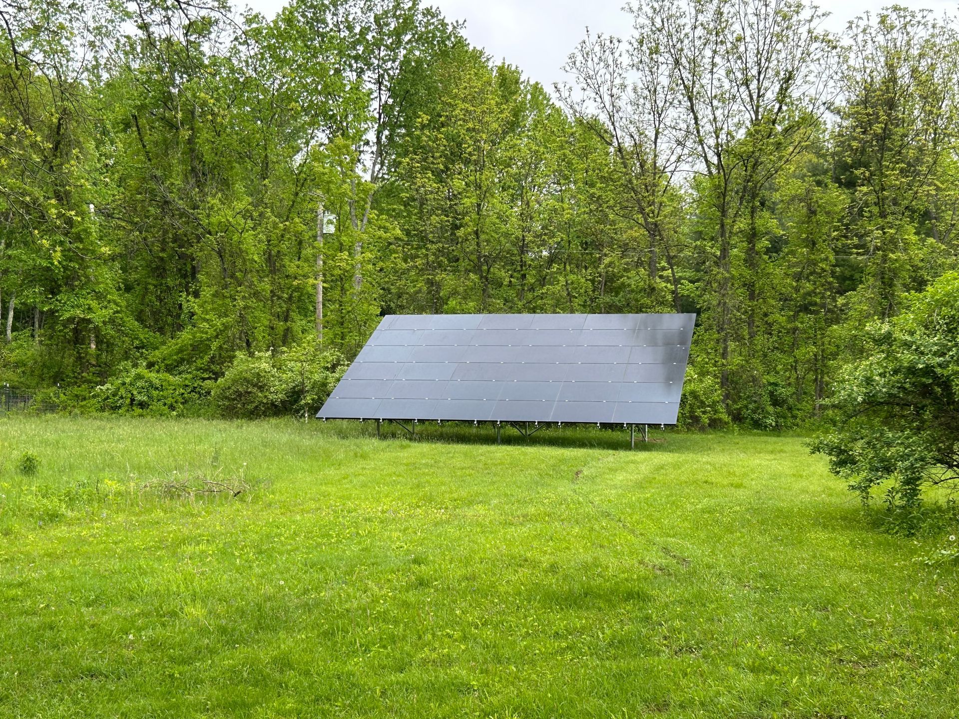A solar panel is sitting in the middle of a grassy field.