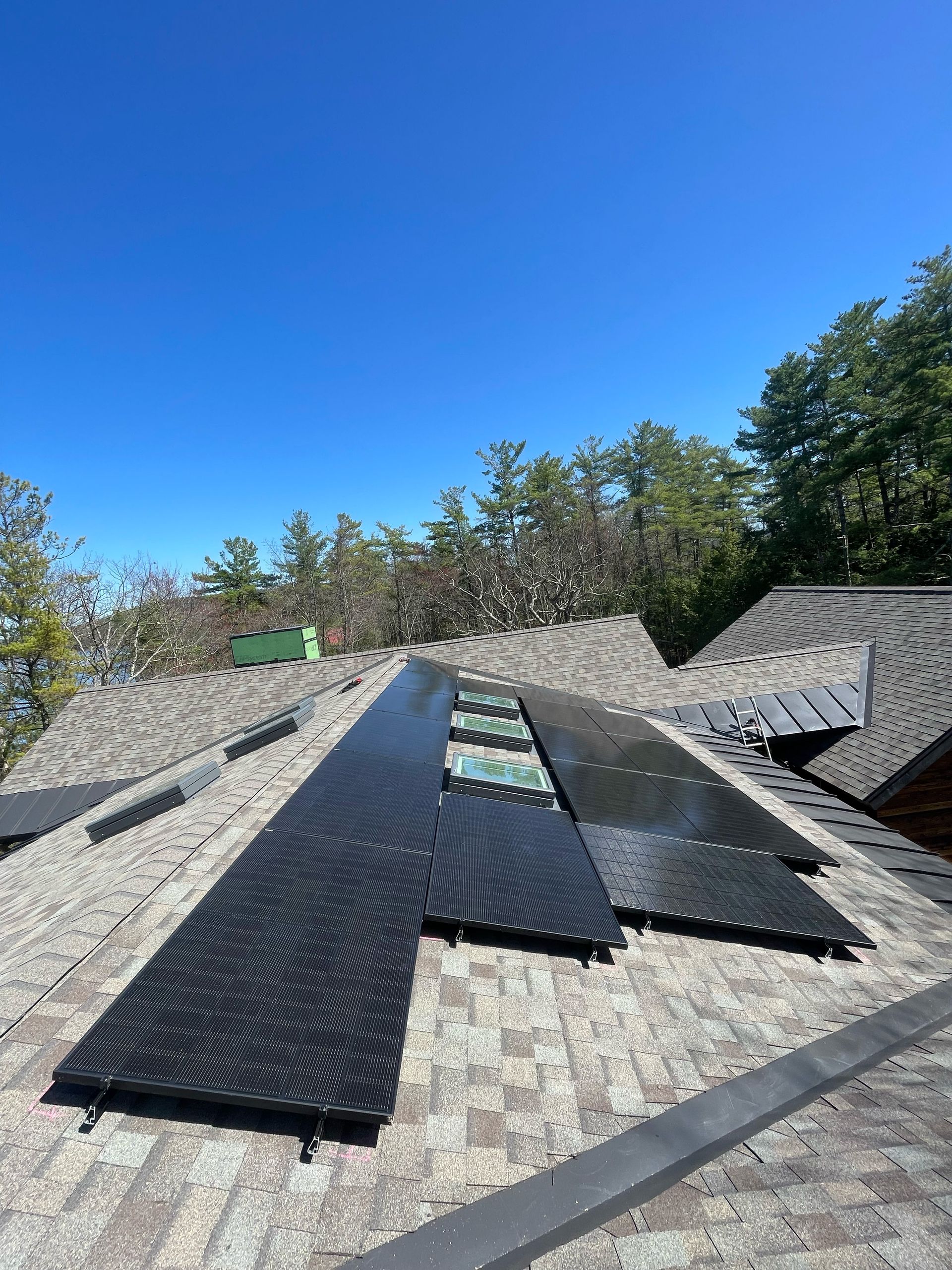 There are many solar panels on the roof of a house.