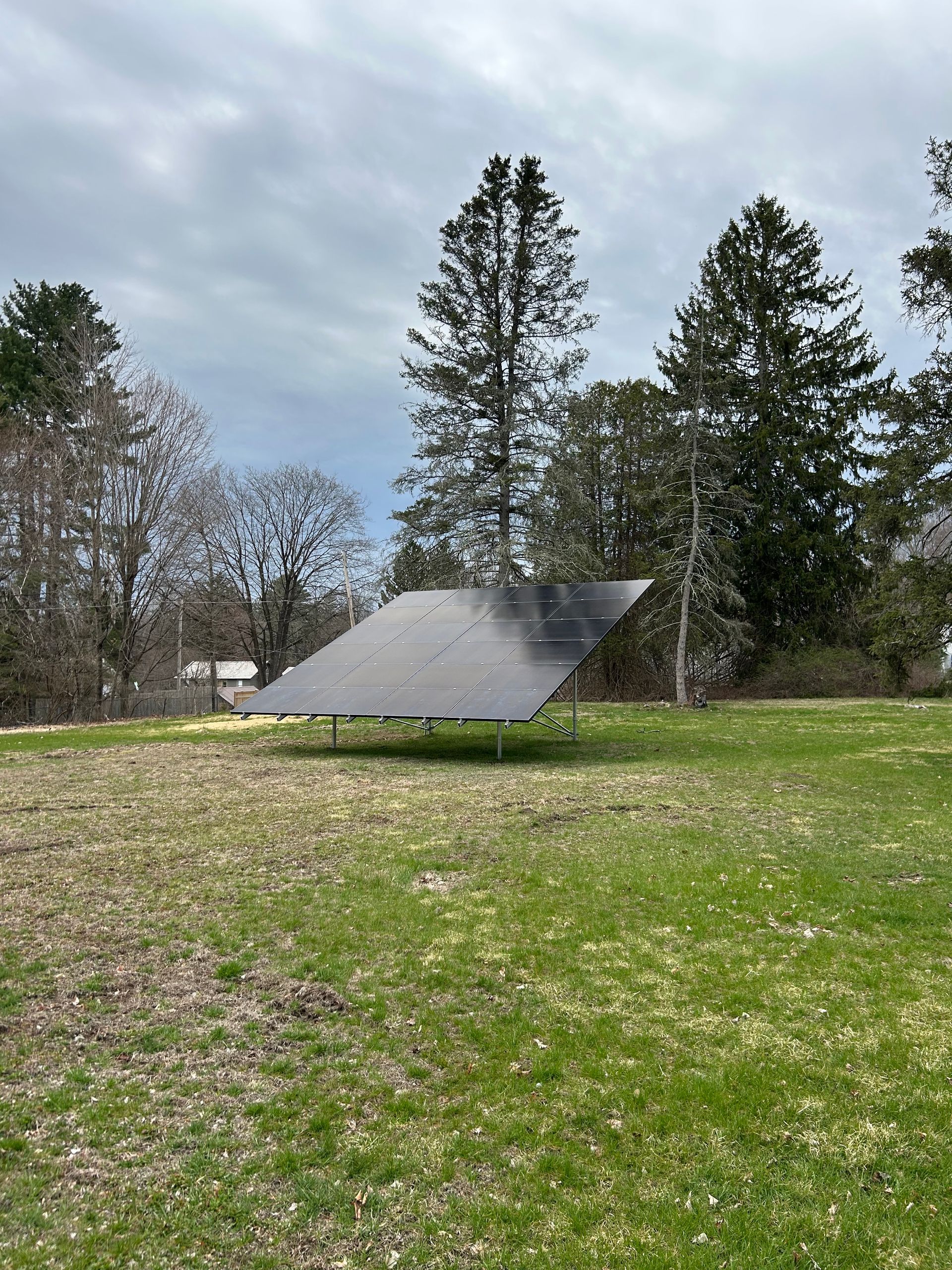 A solar panel is sitting in the middle of a grassy field.