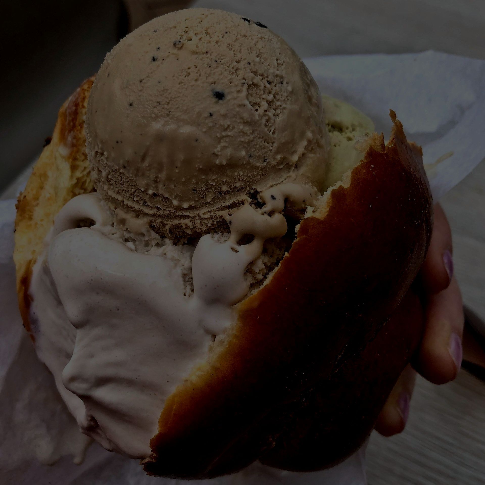 Una persona tiene in mano un panino con il gelato sopra
