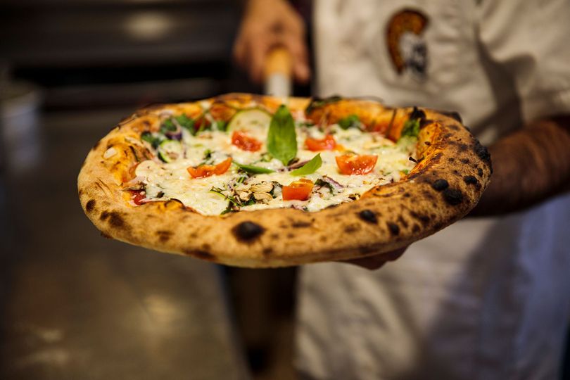Una persona tiene una pizza in mano.