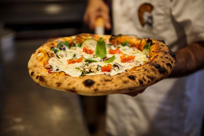 Una persona tiene una pizza in mano.
