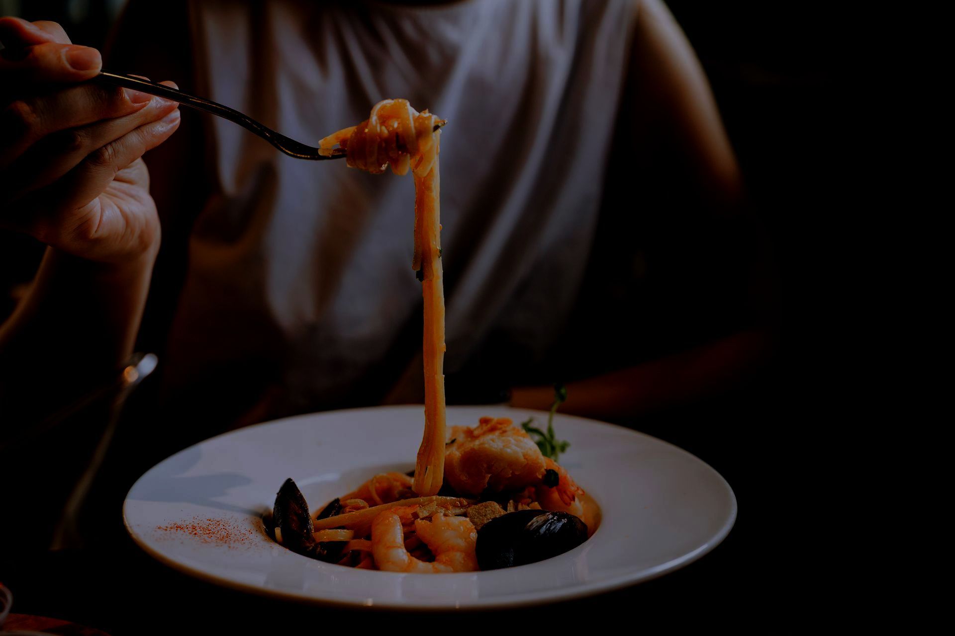 Una persona sta mangiando la pasta con una forchetta da un piatto.