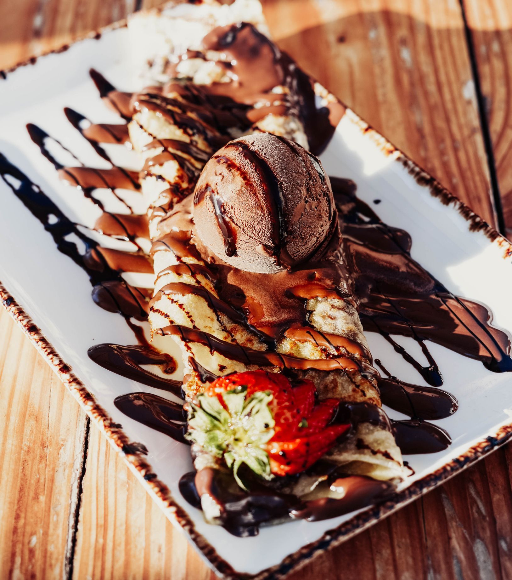 Un piatto di cibo con salsa al cioccolato e una fragola sopra