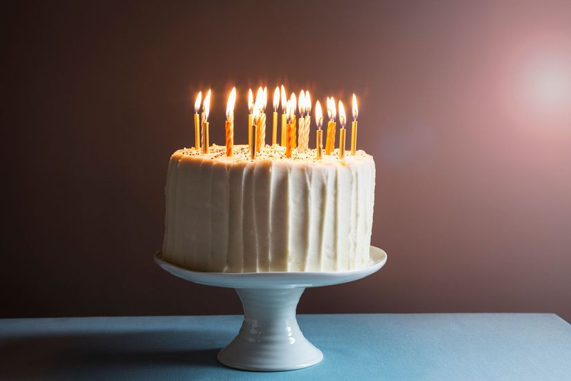 Una torta di compleanno con tante candeline accese su un tavolo.