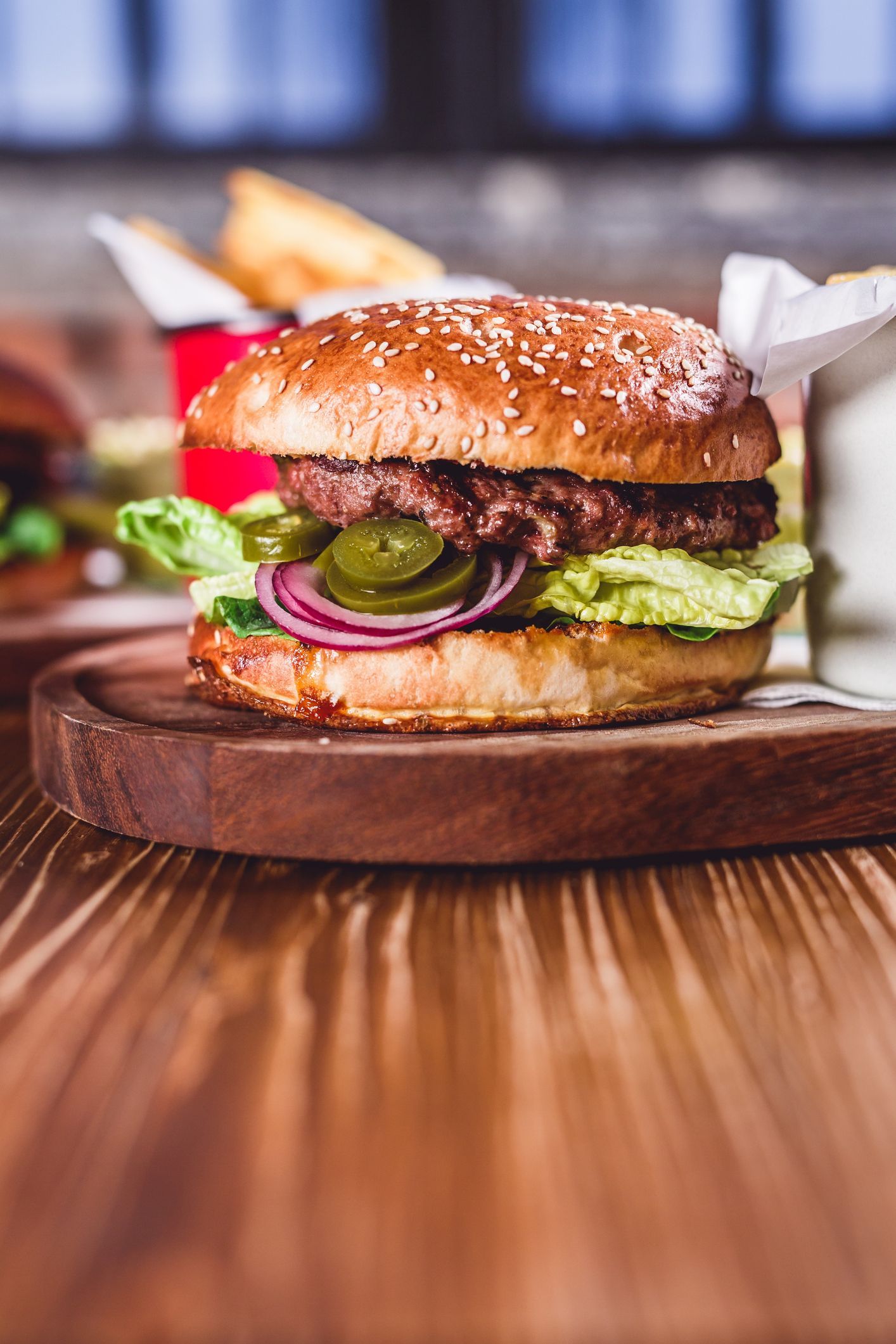 Un hamburger è appoggiato su un tagliere di legno su un tavolo di legno.