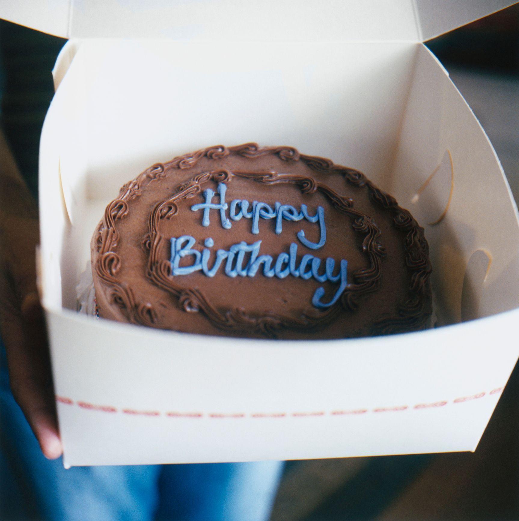 Una persona tiene in mano una torta con la scritta