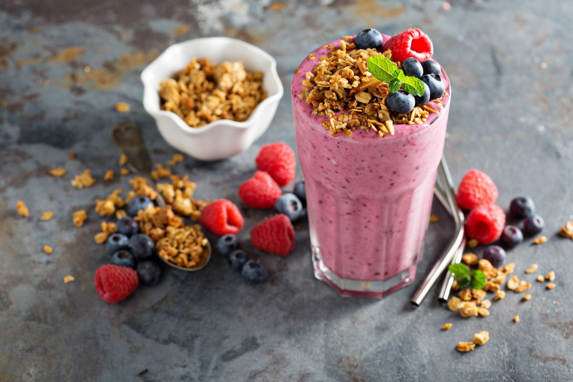 Un frullato con lamponi, mirtilli e granola in un bicchiere su un tavolo.