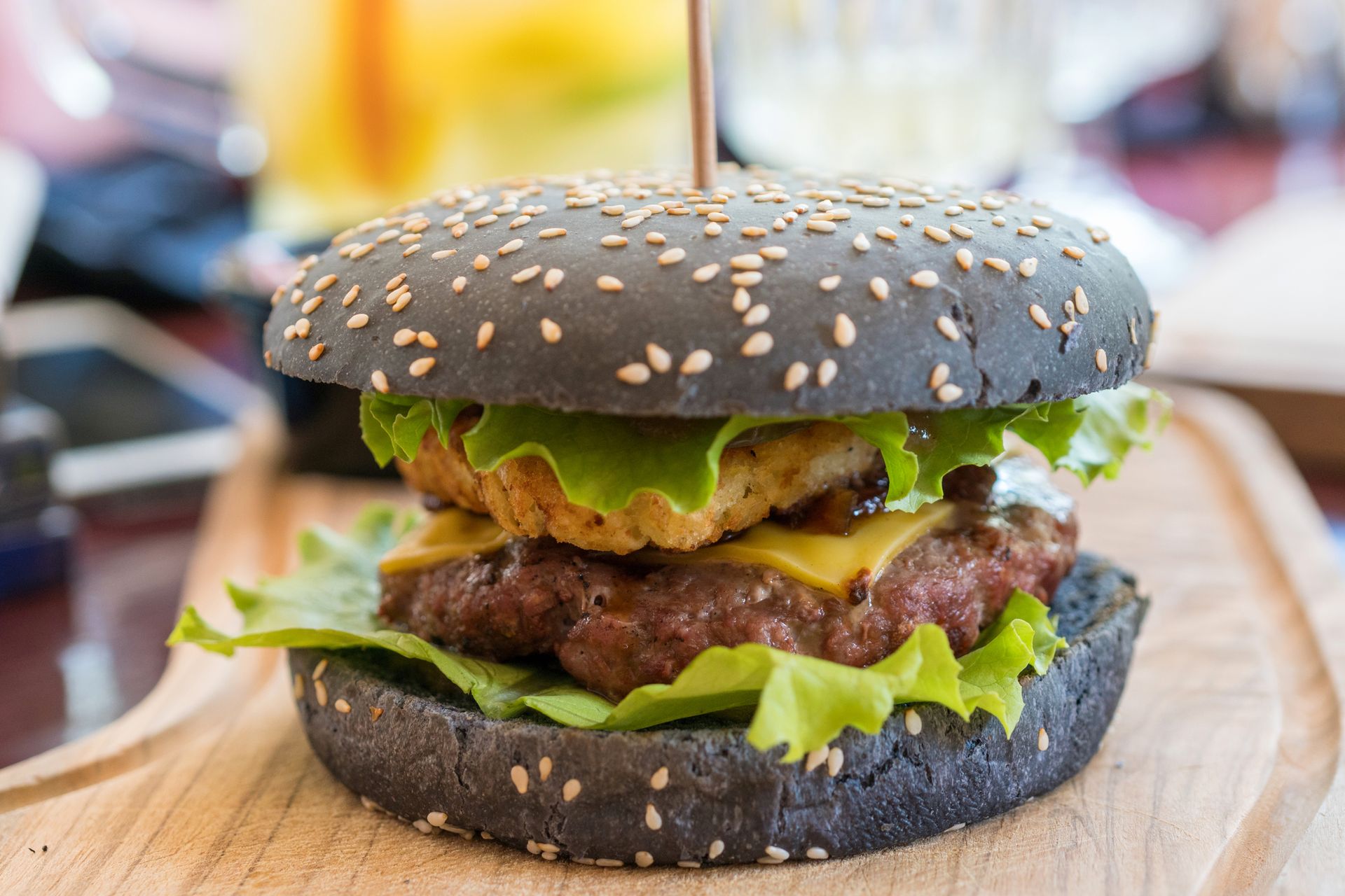 Un hamburger nero è appoggiato su un tagliere di legno.