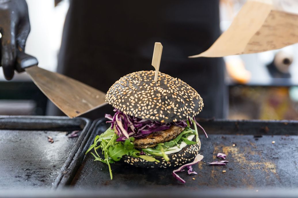 Una persona sta cucinando un hamburger su una griglia con una spatola.