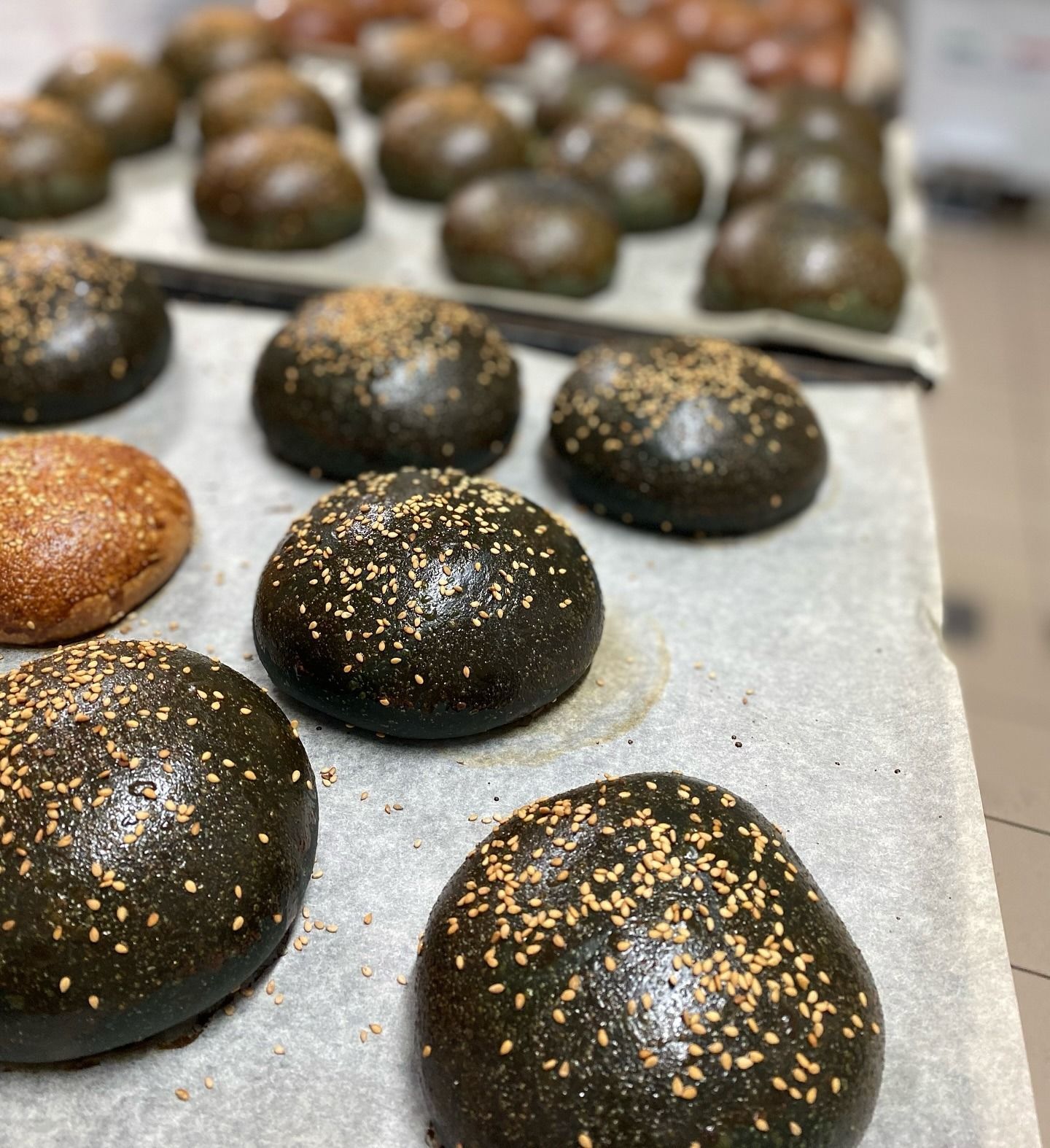 Un mucchio di panini neri per hamburger sono appoggiati su un tavolo.