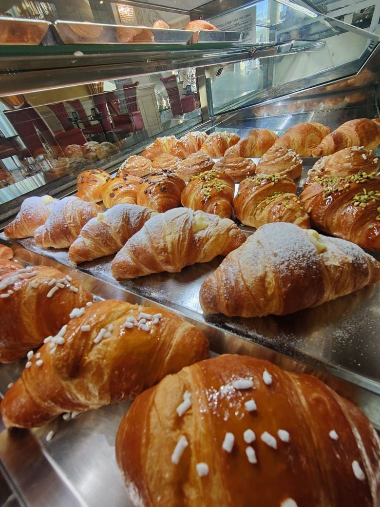 Una vetrina piena di croissant e pasticcini in una panetteria.