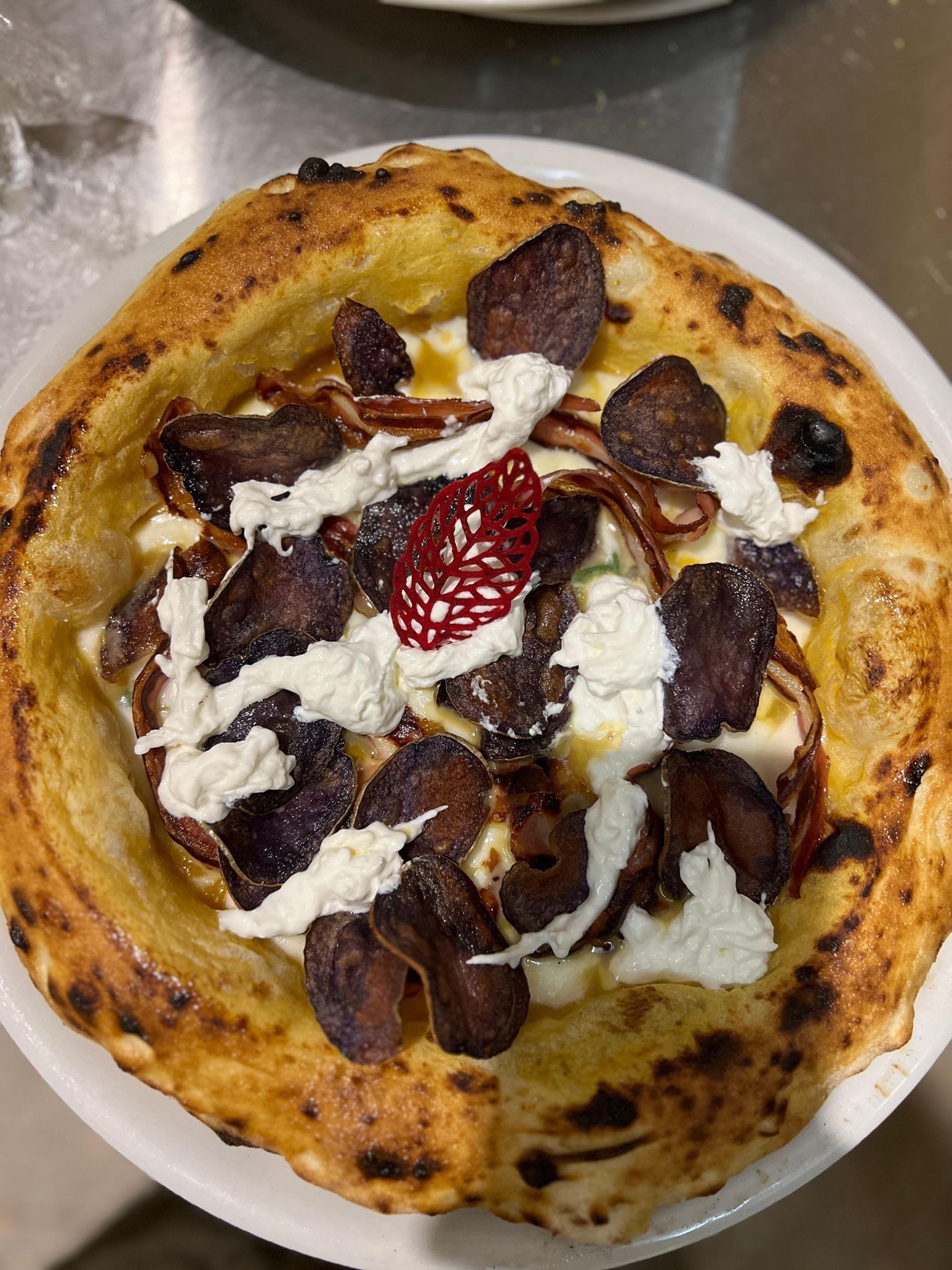 Una pizza con tanti condimenti è servita su un piatto bianco.
