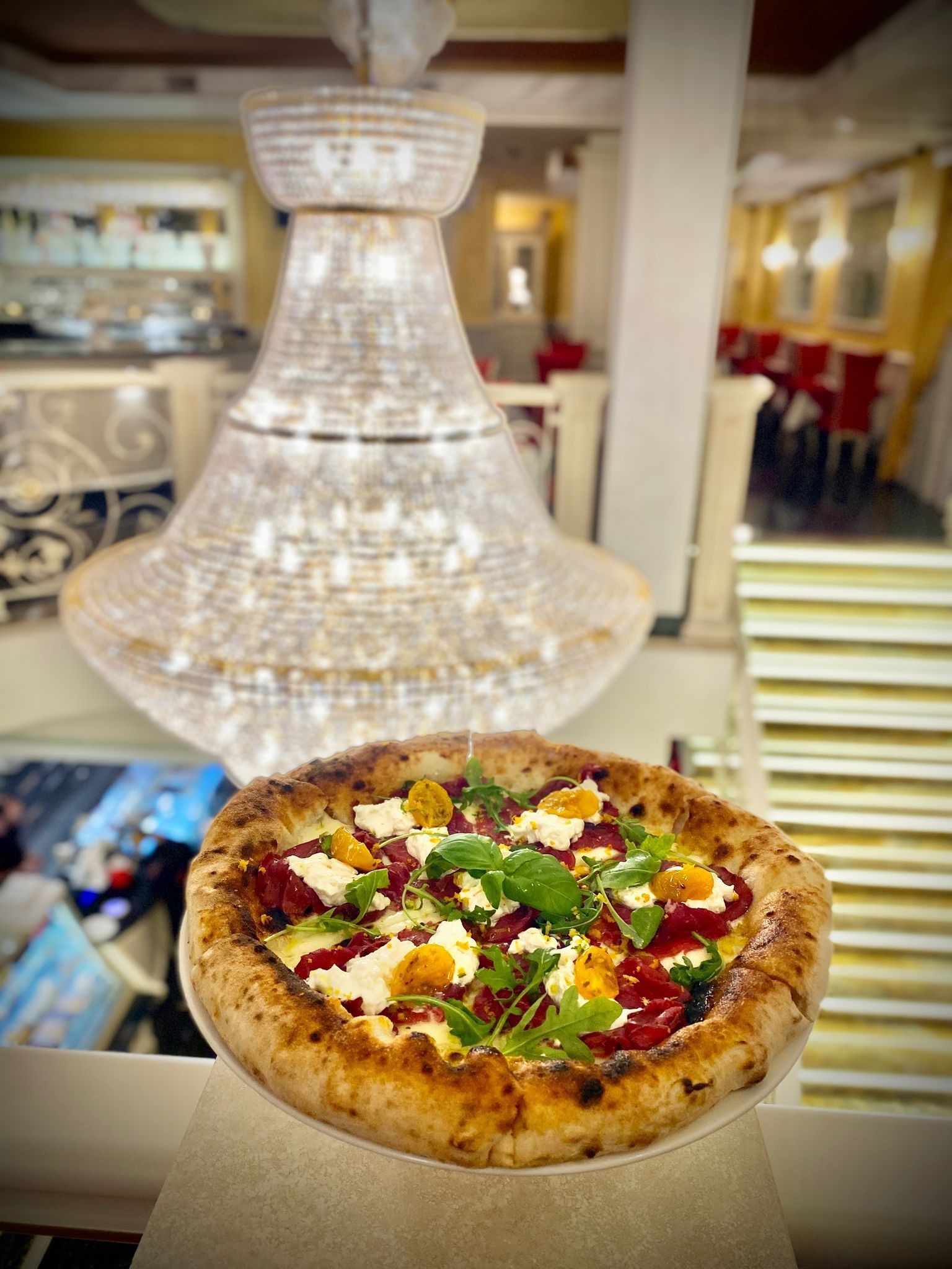 Una pizza è appoggiata su un tavolo davanti a un lampadario.