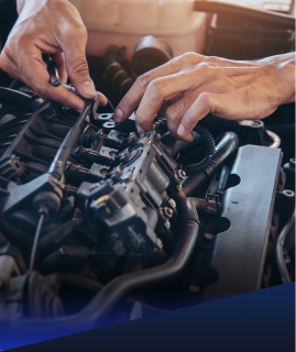 Close-up of hands working on an open car engine, adjusting components and wiring in an automotive repair setting. | Heaven Sent Automotive