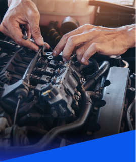 Close-up of hands working on an open car engine, adjusting components and wiring in an automotive repair setting. | Heaven Sent Automotive