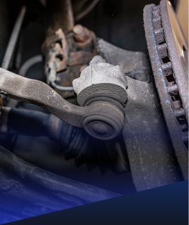 A close-up view of a vehicle's suspension system, showing a tie rod end connected to the wheel knuckle. | Heaven Sent Automotive